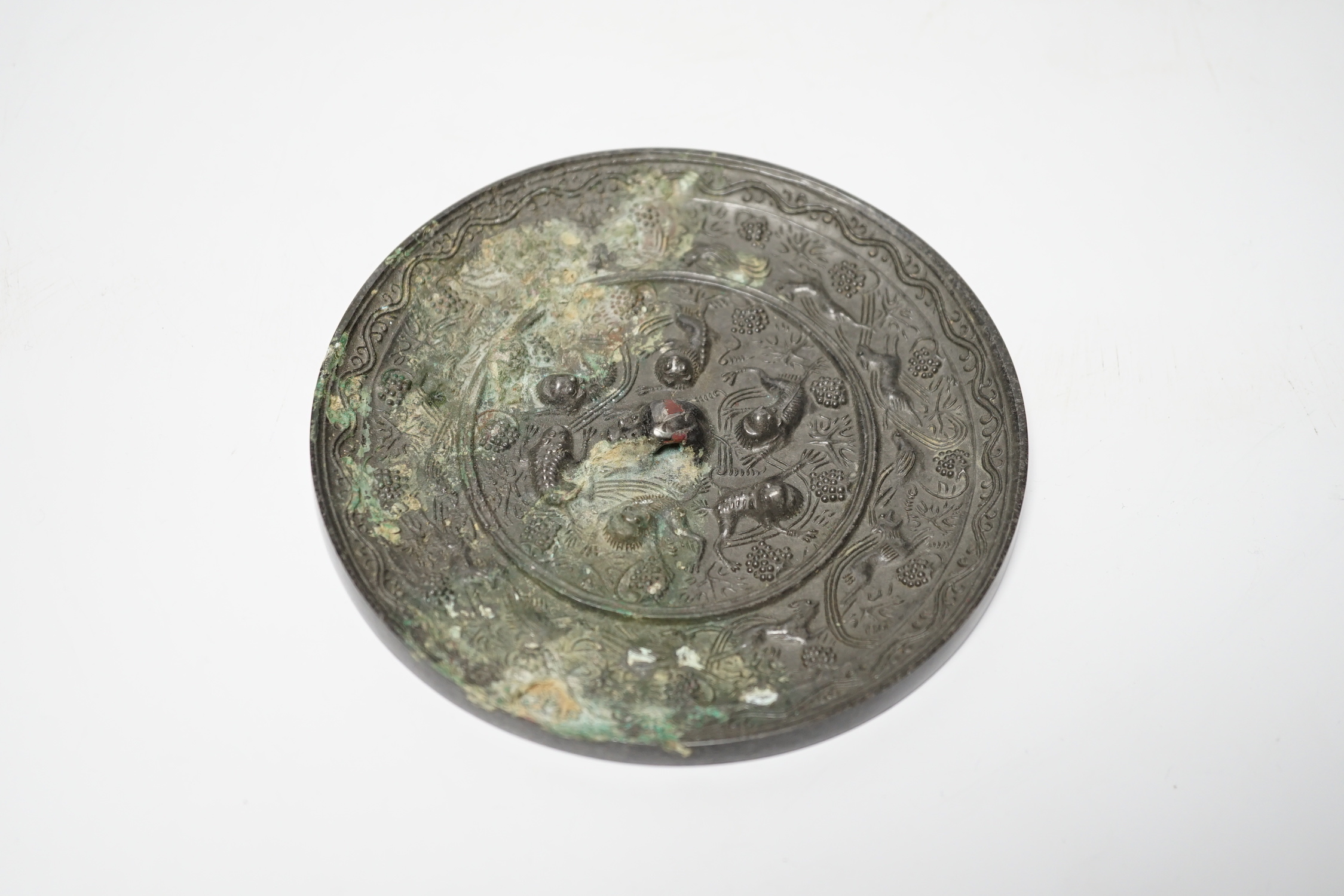 A Chinese cast bronze mirror, decorated with vines, and mythical creatures, diameter 12.5cm